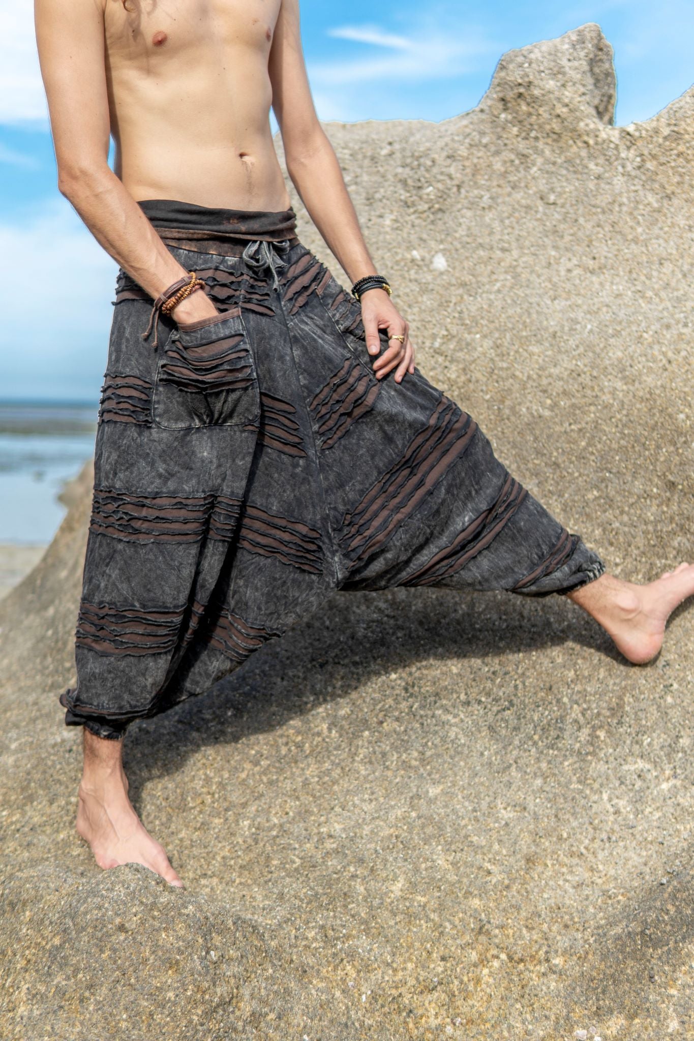Close-up of men's alternative charcoal grey trousers featuring distressed razorcut detailing, oversized pockets and a brown underlay.