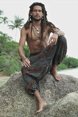 Relaxed lifestyle photo of men's charcoal boho razorcut drop crotch pants with a rust orange underlayer.