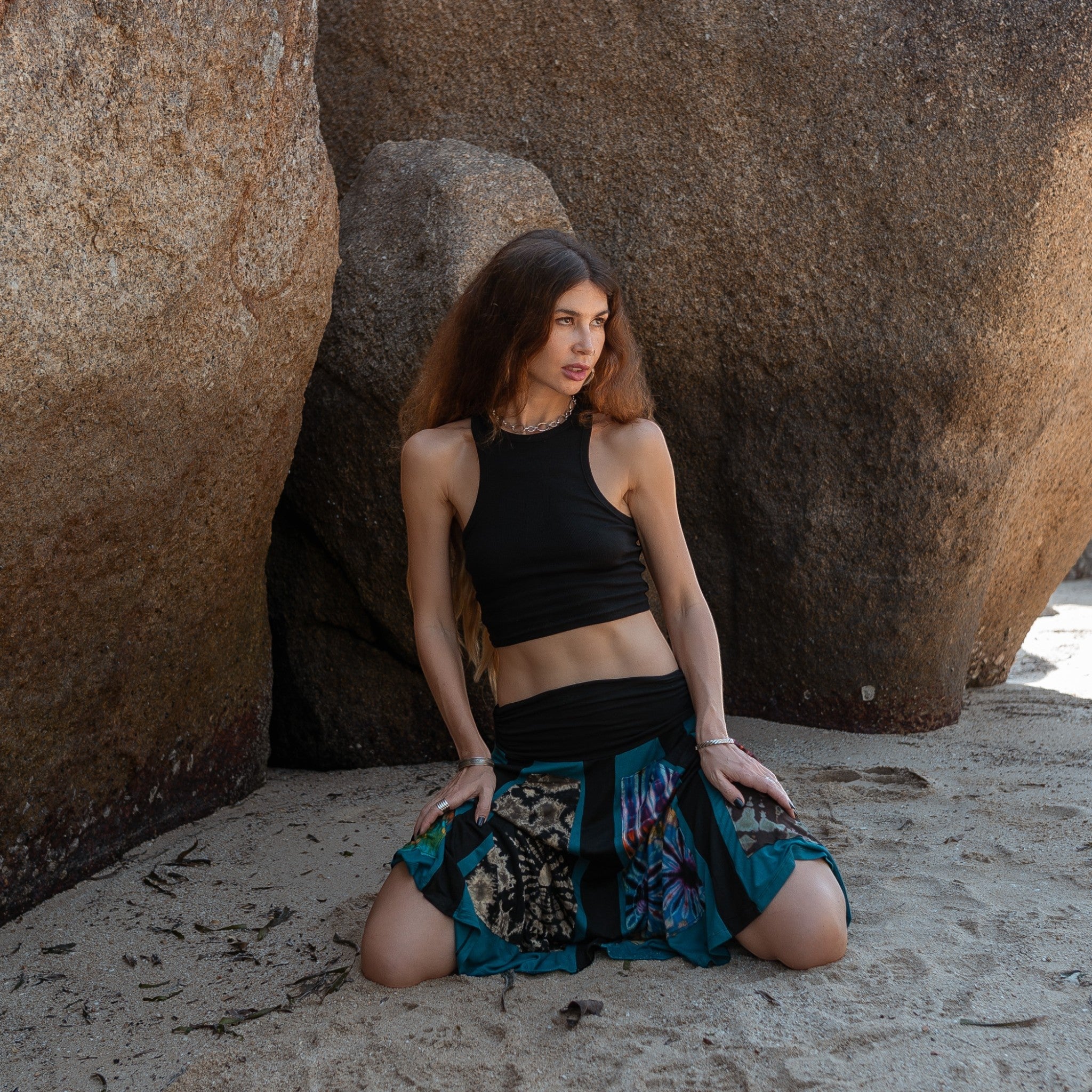 woman kneeling wearing a colourful panel midi skirt that's perfect for hippie and trance festivals and parties