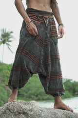 View of men's charcoal drop crotch razorcut harem pants where a rust orange underlayer appears under a handcrafted distressed finish.