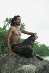 Side profile of a man wearing charcoal grey stonewashed bohemian drop crotch trousers with maroon razorcut detailing and elasticated ankles.