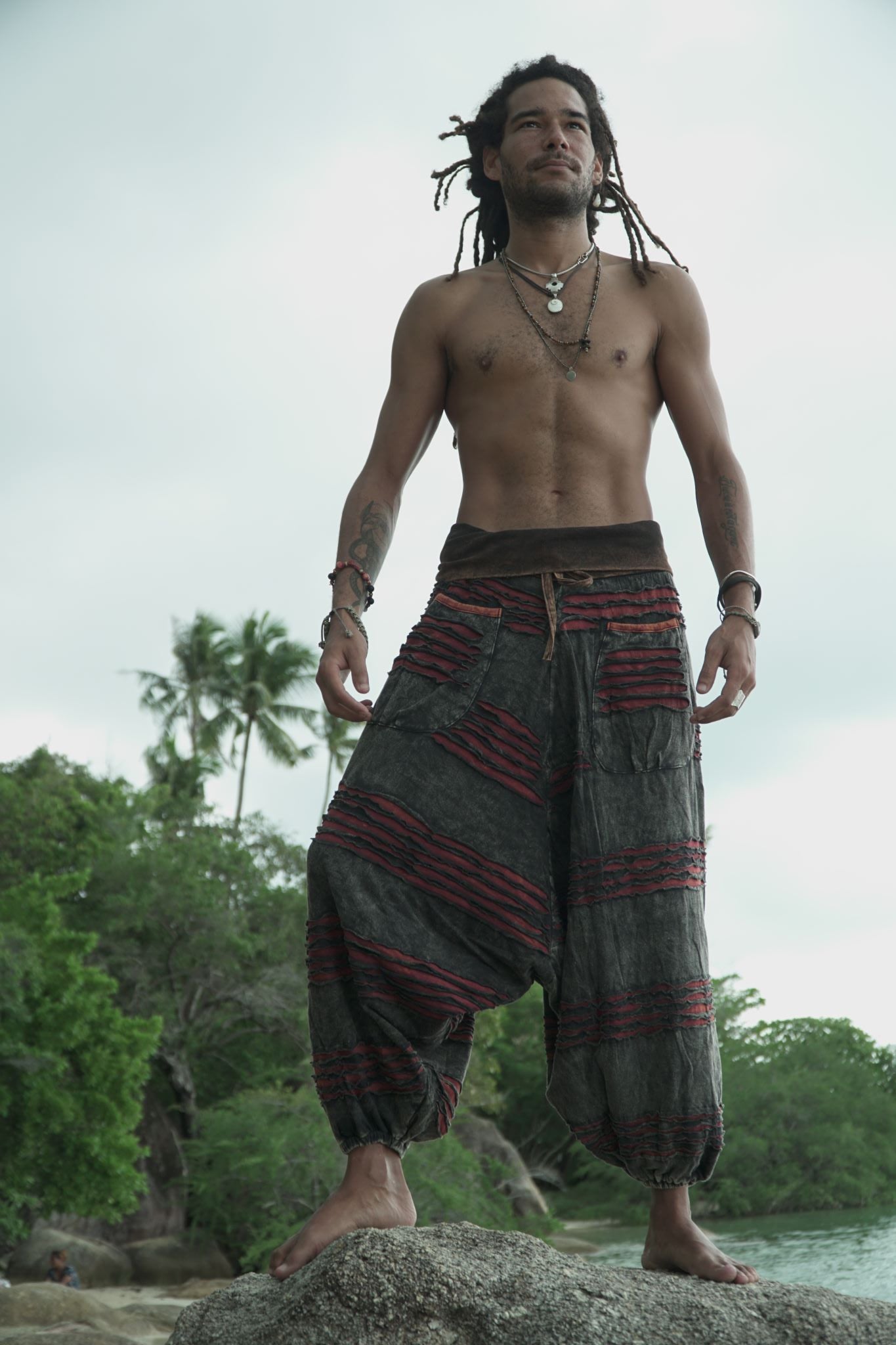 Man modelling charcoal grey stonewashed bohemian harem pants with maroon razorcut detailing, relaxed drop crotch fit and elasticated ankles.