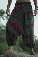 Front view of a man wearing charcoal grey stonewashed drop crotch trousers with a maroon razorcut underlay, elasticated waistband and ankle cuffs.