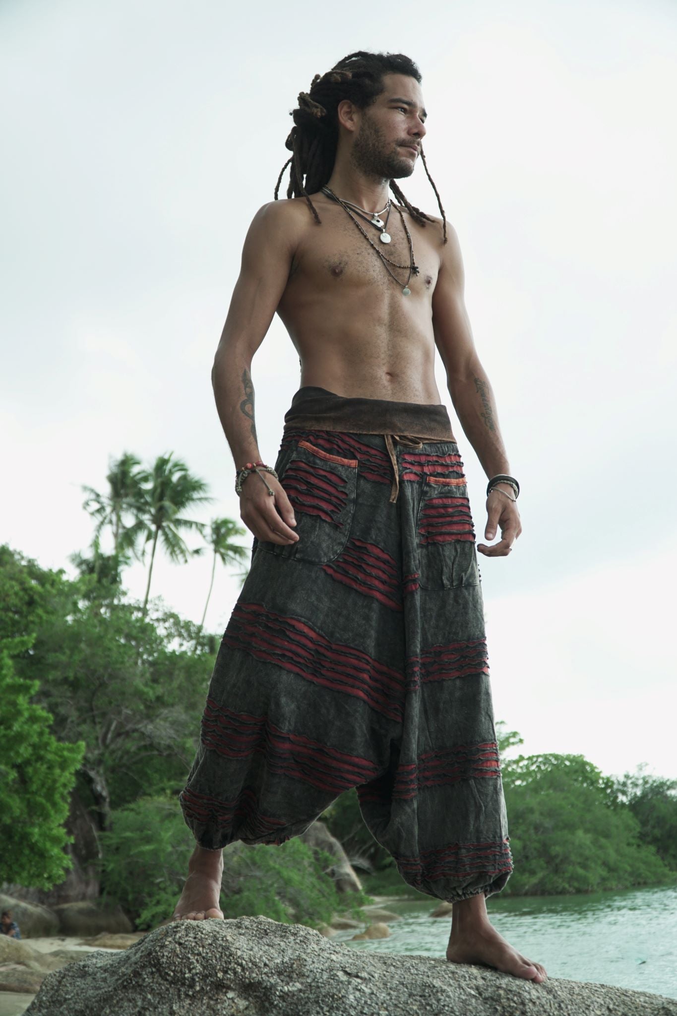 Side view of charcoal grey stonewashed drop crotch harem pants with a maroon razorcut underlayer and handcrafted layered detailing.