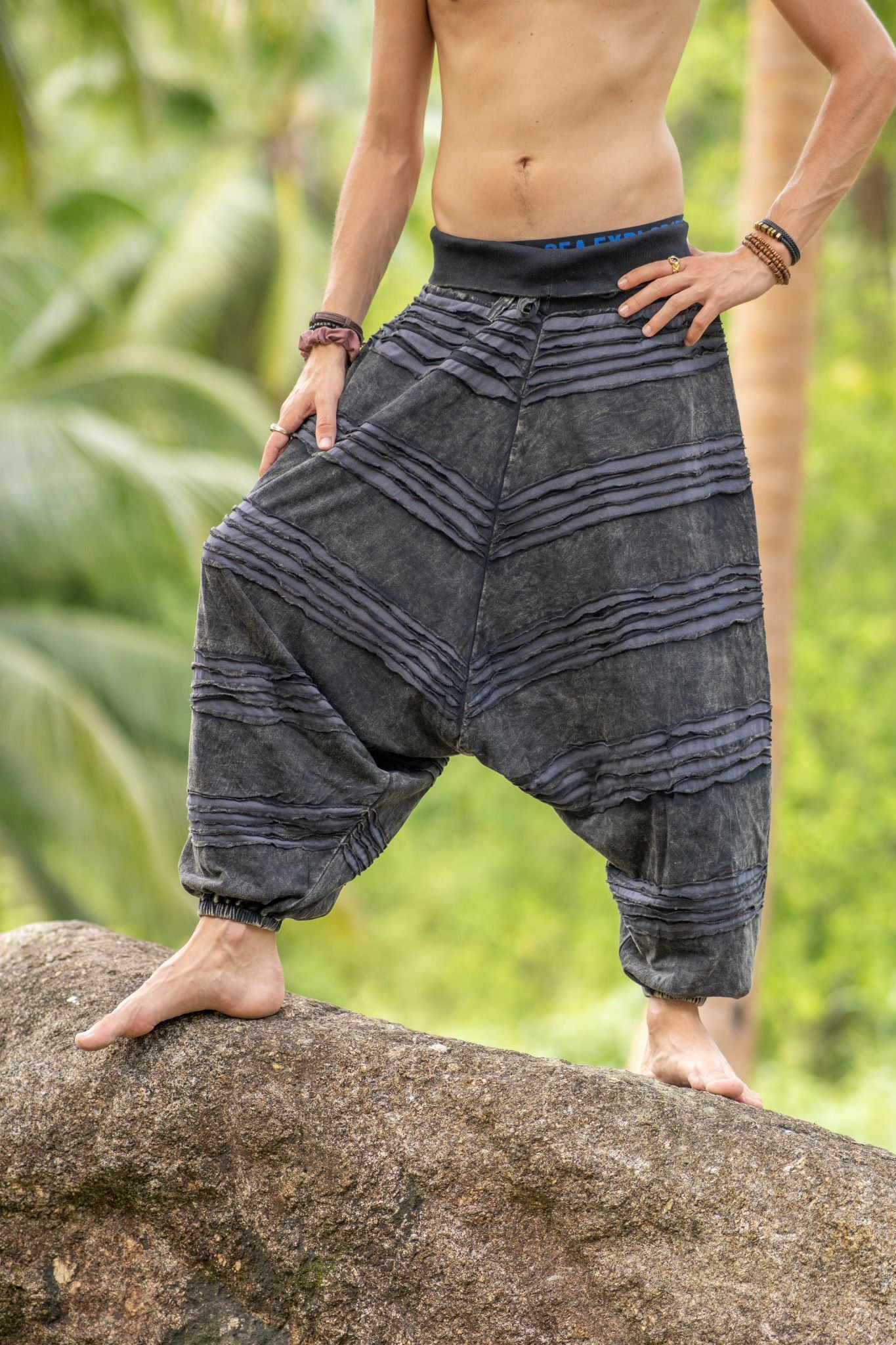 Detailed front view of grey stonewashed cotton men's drop crotch trousers, highlighting the handcrafted razorcut design, textured fabric and relaxed boho fit.