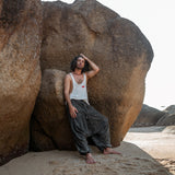 an leaning against rock wearing charcoal grey stonewashed drop crotch harem pants, boho festival style