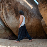 Man walking barefoot on beach wearing navy stonewashed drop crotch harem pants, boho festival style