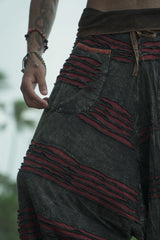 Close-up of the front pocket and handcrafted razorcut detailing on charcoal grey men's harem pants with a maroon underlayer.