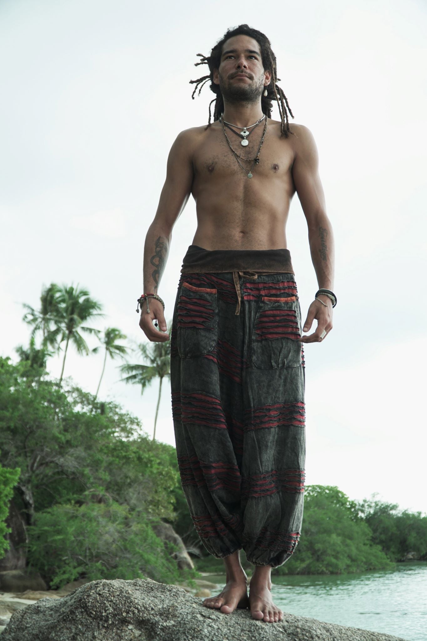 Front view of charcoal grey stonewashed boho trousers with a maroon razorcut underlay, relaxed drop crotch styling and elasticated ankles.