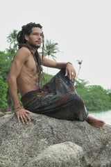 Side view of men's charcoal stonewashed razorcut harem pants with a rust orange underlayer, photographed outdoors.