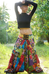 Women's multicolour patchwork harem pants, full length front view showing wide flared legs and decorative button waistband, worn outdoors