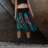 Model standing in a teal patchwork mid length skirt, styled with black boots and a crop top
